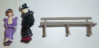 TWO UNIDENTIFIED WHITE METAL MODELS OF VICTORIAN LADIES SITTING ON A BENCH 2