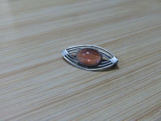 A Small Vintage Oval Shaped Sterling Silver Brooch Set With An Amber Stone